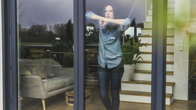 Woman staring out sliding glass doors in isolation