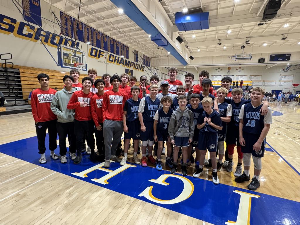 A group of young basketball players pose for a team photo on the court.