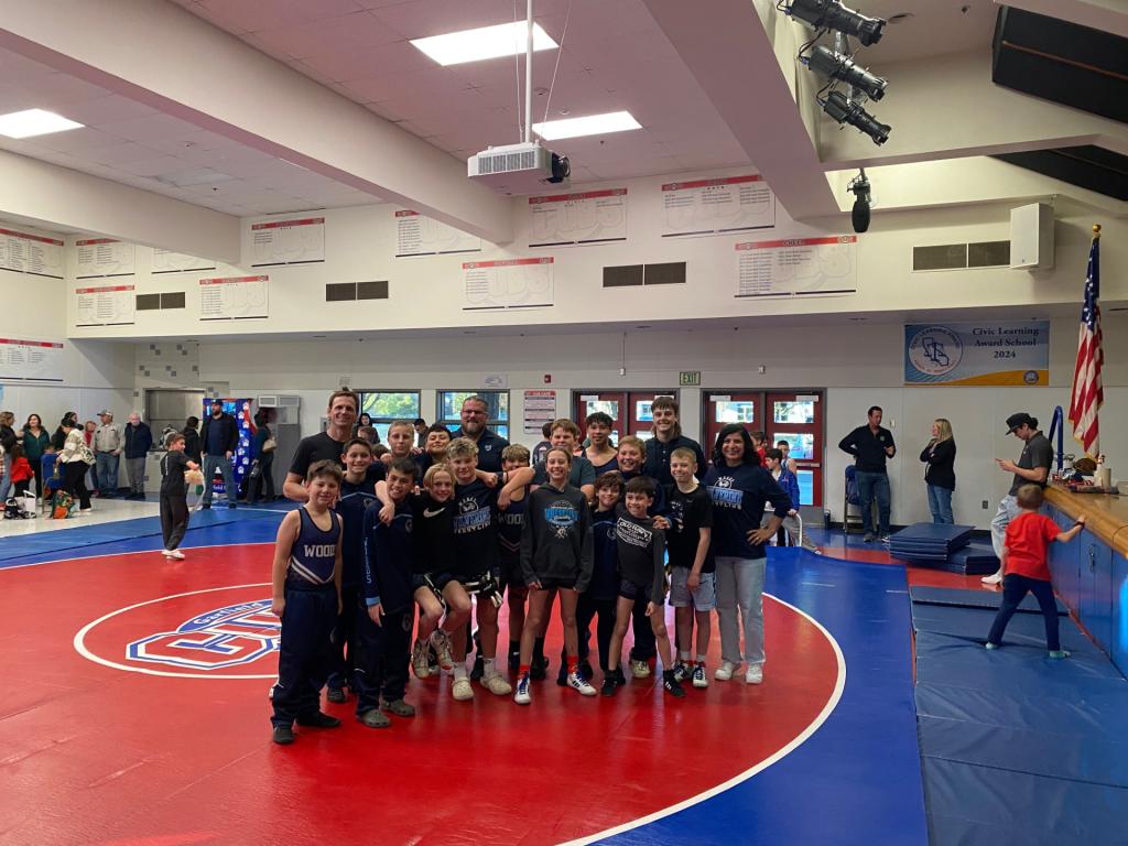 A wrestling team poses for a group photo on a red and blue mat.