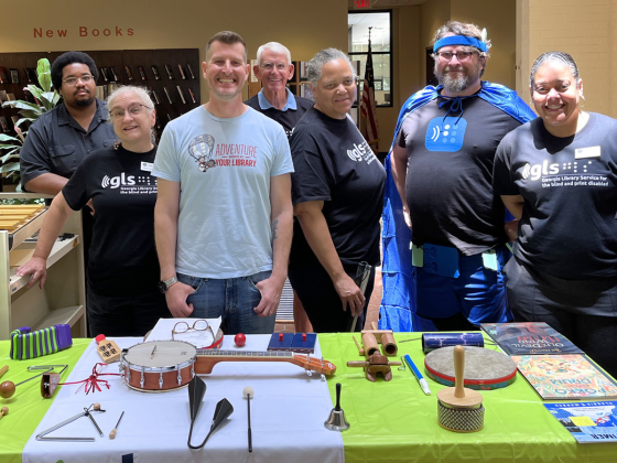 GLS staff stand behind a table with musical instruments.