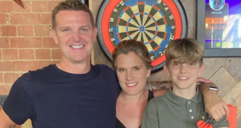 A man with short brown hair has his arm around a blonde haired woman and young blonde teenager.