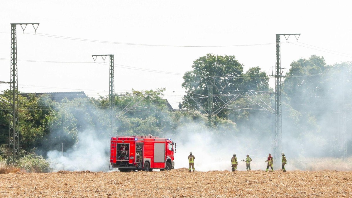 Feuerwehrleute bei Löscharbeiten an einer Bahnstrecke. Nach einem Böschungsbrand bleibt die wichtige Bahnstrecke zwischen Düsseldorf und Köln bis mindestens Samstagnachmittag gesperrt. Im Nah- und Fernverkehr kommt es deshalb zu Umleitungen und Verspätungen. Bahnstrecke Düsseldorf-Köln bis Samstag gesperrt