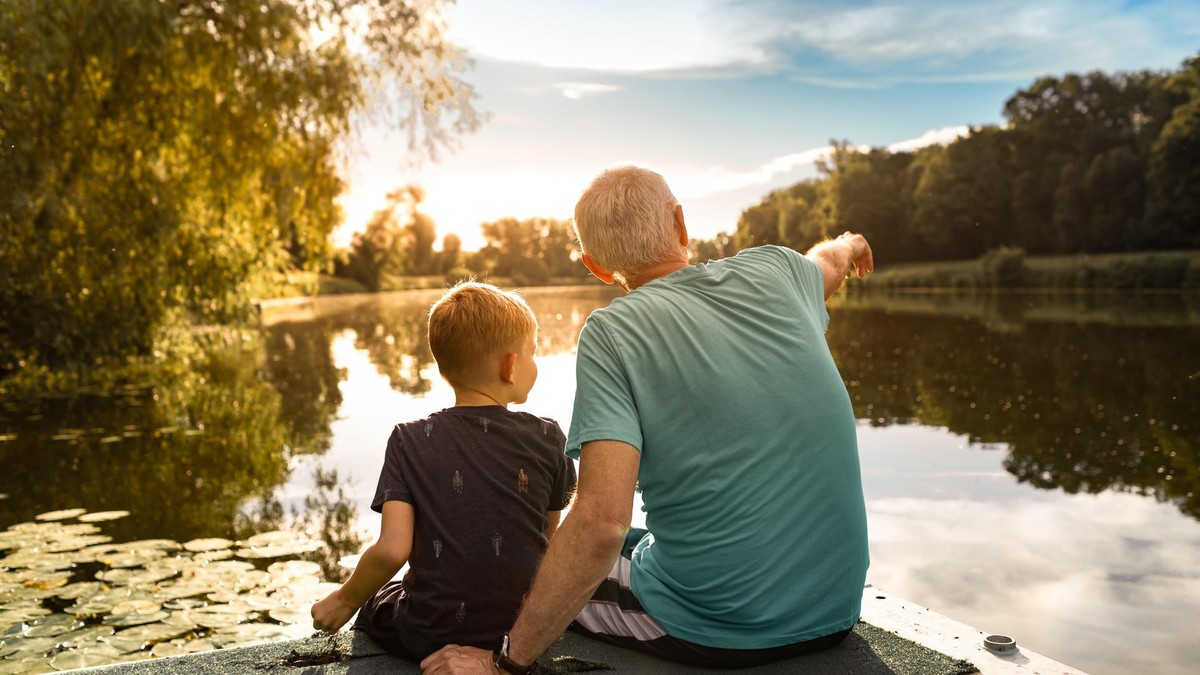 Die Deutschen leben im Durchschnitt länger. Neue Studien zeigen jedoch, dass sich die Lebenserwartung regional und sozial zunehmend unterschiedlich entwickelt. Young boy and his grandfather spending time at the park forest lake.