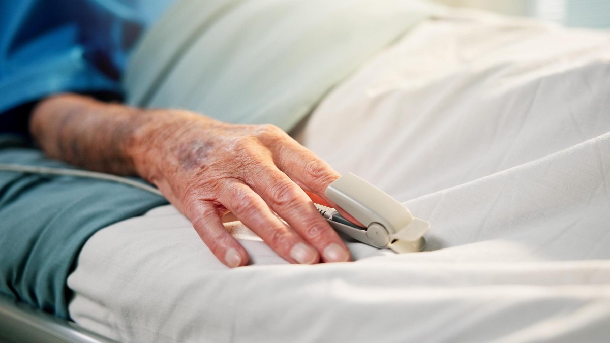 Für kranke Personen, die in Frankreich leben, soll Sterbehilfe zukünftig möglich sein. Die Hand einer älteren Person mit Pulsmesser am Finger auf einem Krankenbett