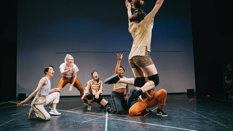 A group of dancers watch as one dancer jumps A group of dancers watch as one dancer jumps