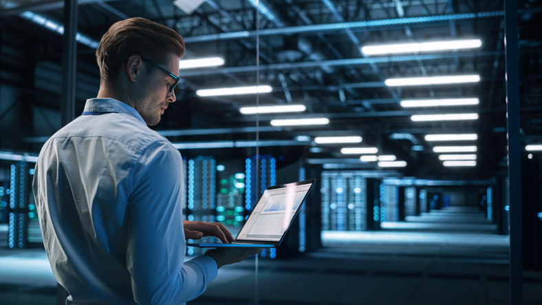 Man on a laptop, working in a data center.