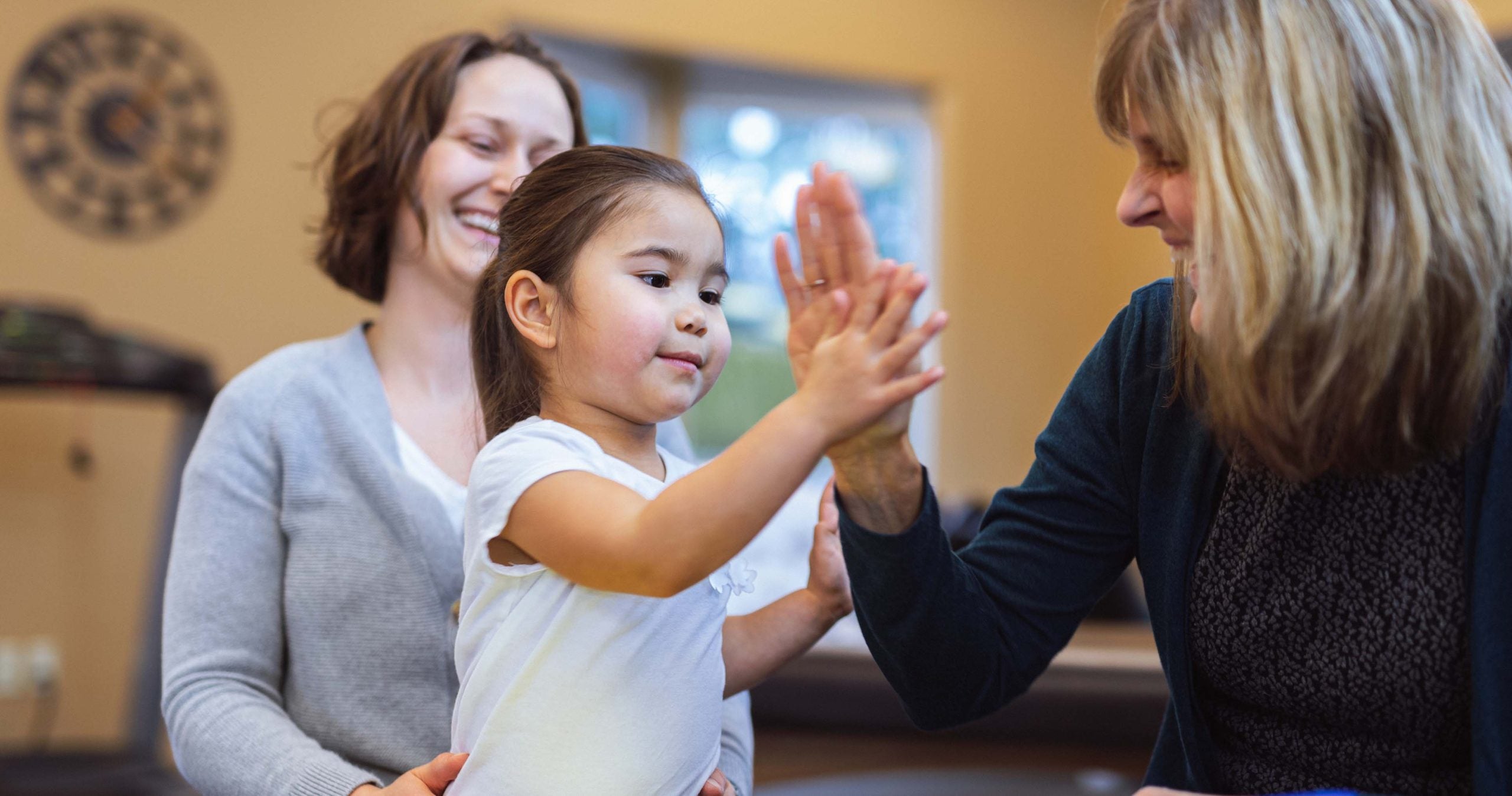 Child with her parent giving a social worker a high five
