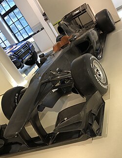 A black Formula One car displayed in a museum.