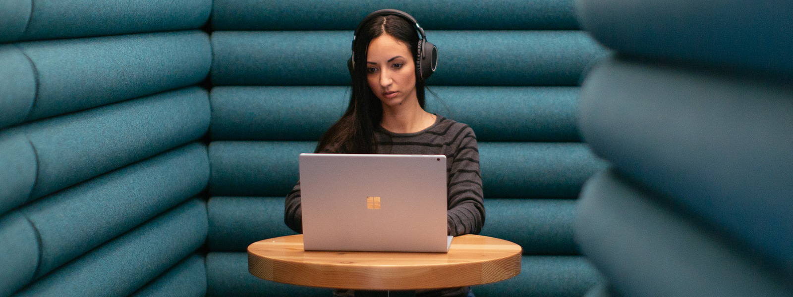 A woman sits quietly in solitude while wearing headphones as she works on her Windows 10 computer
