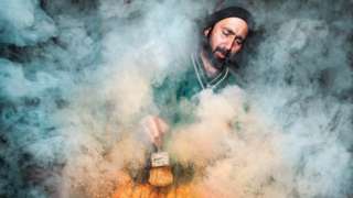 Street food vendor surrounded by smoke as they prepare food