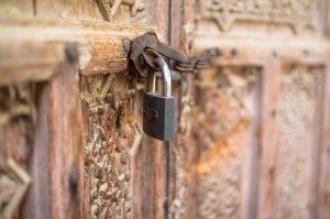 A padlock and chain securing a carved wooden door