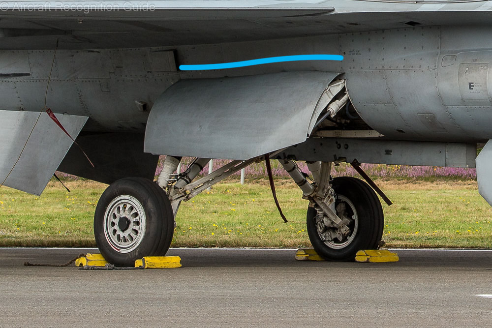 The main landing gear door of the Block 40 F-16 and subseqent versions has a curved hinge edge at the top. This is straight on earlier versions. Also note the wheel rims have fewer holes. Image