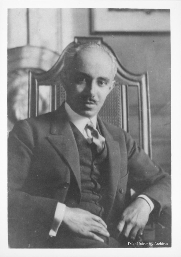 Black-and-white portrait of architect Julian Abele seated in a chair wearing a suit and tie.
