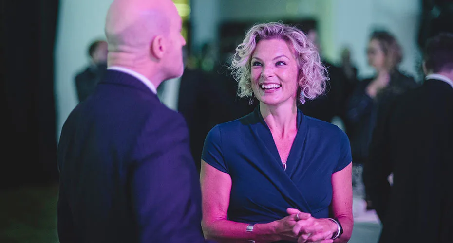 A man and woman in professional clothing engaged in a smiley conversation