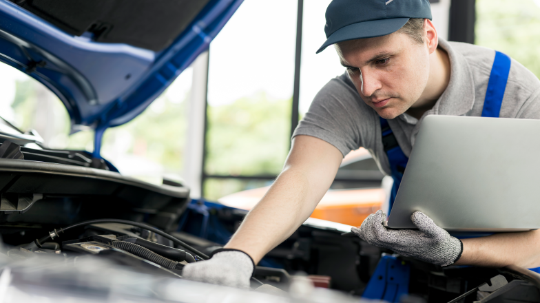 technical professional reviewing vehicle with device in hand