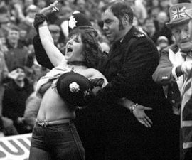 With a police helmet covering her assets, Erika Roe is escorted from the pitch. Photo: Press Association
