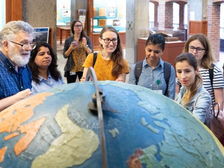 A group of students standing in a circle in front of a large globe