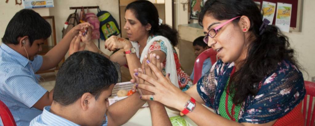 Two female teachers working with young male students in a classroom.