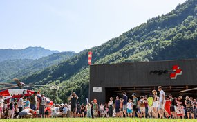 Viele Menschen vor einem Helikopterhangar, die einen ausgedtellten Helikopter betrachten.