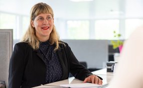 Kelly Gray, Teamleiterin Einsatzmanagement bei der Rega, lächelnd an ihrem Pult im Büro.