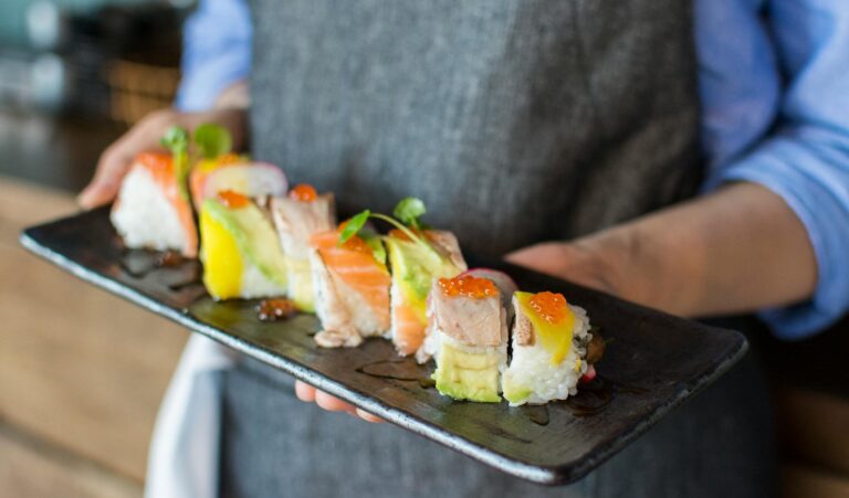 A Plate Of Sushi Rolls With Different Ingredients Like Tangy Rice, Imitation Crab, Sesame Seeds, and Spicy Mayo And Unagi Sauce