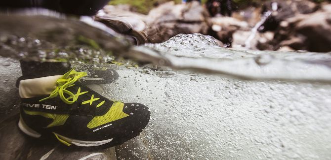 Nahaufnahme eines Schuhs beim Canyoning im fließenden Wasser.